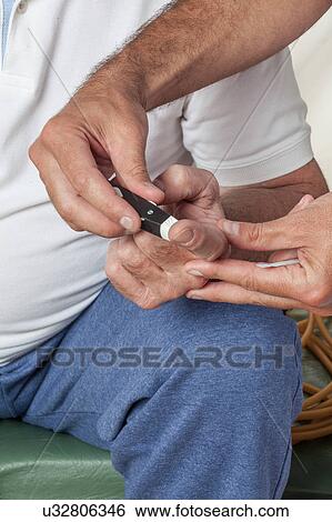 Stock Photograph - Elder man using the Glucose meter. Fotosearch