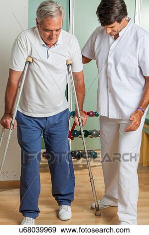 Stock Photo - Elder man with his doctor rehabiliting. Fotosearch