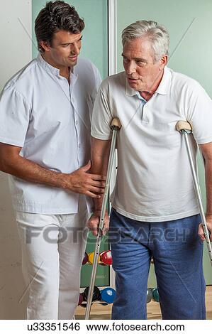 Stock Photograph - Elder man with his doctor rehabiliting. Fotosearch