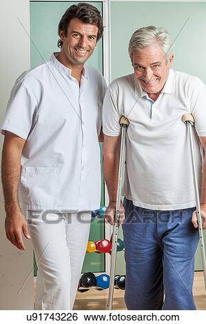 Stock Photograph - Elder man with his doctor rehabiliting. Fotosearch