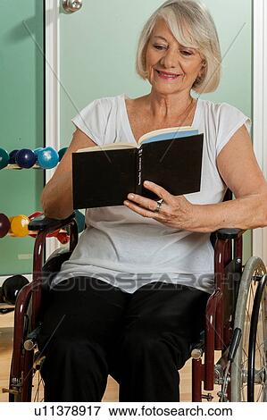 Stock Photo - elder woman in a wheelchair reading a book. Fotosearch