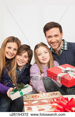 Stock Image - Family smiling giving presents. Fotosearch