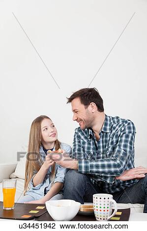 Stock Image - Father having a breakfast with his daughter. Fotosearch