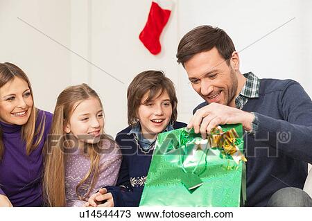 Stock Image - Father open his present with his family. Fotosearch
