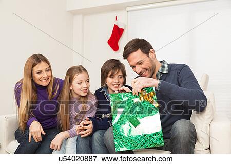 Stock Photo - Father open his present with his family. Fotosearch