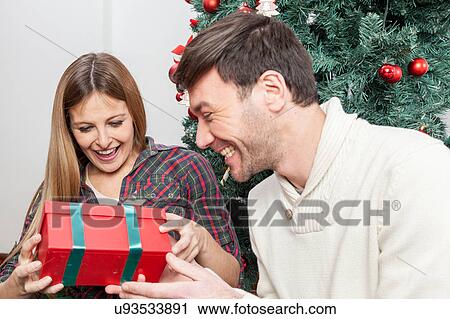 Fun couple opening a christmas gift View Large Photo Image Stock Image - Fun couple opening a christmas gift. Fotosearch