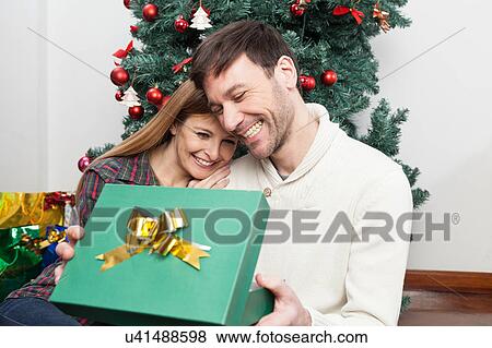 Stock Photo - Fun couple opening a christmas gift. Fotosearch