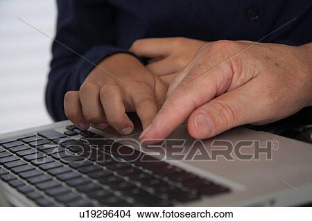 Picture - Girl helping to her grandfather with the computer. Fotosearch