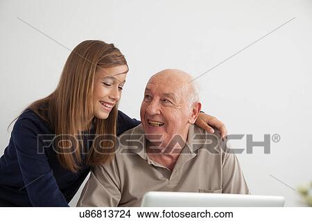 Picture - Girl helping to her grandfather with the computer. Fotosearch