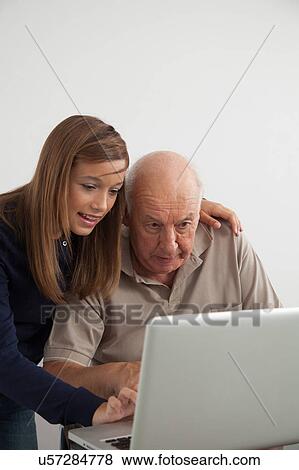 Stock Photo - Girl helping to her grandfather with the computer. Fotosearch