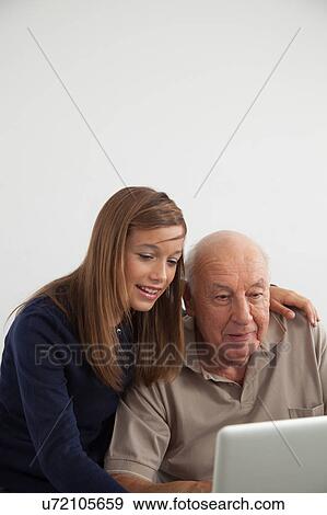 Stock Photo - Girl helping to her grandfather with the computer. Fotosearch