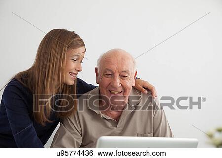 Stock Photograph - Girl helping to her grandfather with the computer. Fotosearch