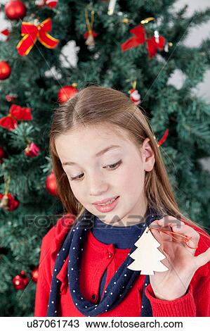 Stock Image - Girl holding a ornament of the christmas tree. Fotosearch