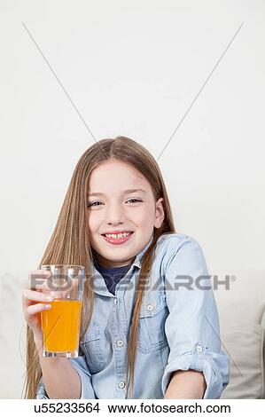 Girl laughing holding a glass with juice View Large Photo Image Picture - Girl laughing holding a glass with juice. Fotosearch