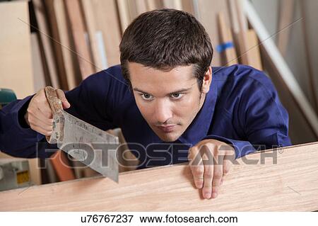 Stock Photo - Guy cutting a piece of wood. Fotosearch