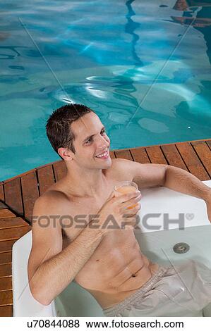 Stock Photo - Guy inside a jacuzzi drinking juice. Fotosearch