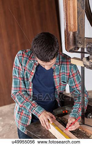 Stock Photograph - Guy measuring a piece of wood. Fotosearch