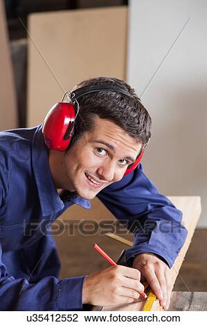 Stock Image - Guy measuring in his workshop. Fotosearch