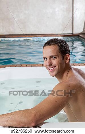 Stock Image - Guy smiling inside a jacuzzi. Fotosearch