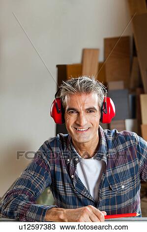 Stock Image - Happy carpenter in his workshop. Fotosearch