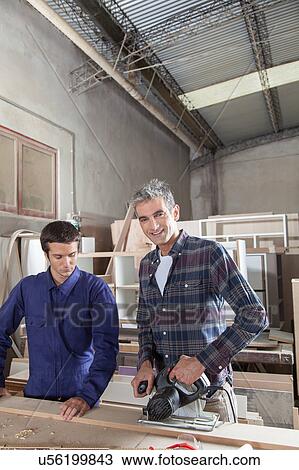 Stock Image - Happy carpenter teaches carpentry. Fotosearch