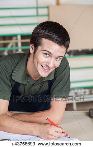 Stock Photo - Happy carpenter writing. Fotosearch