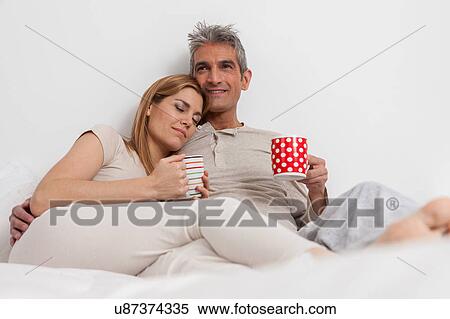 Stock Photography - Happy couple drinking coffe in the bed. Fotosearch