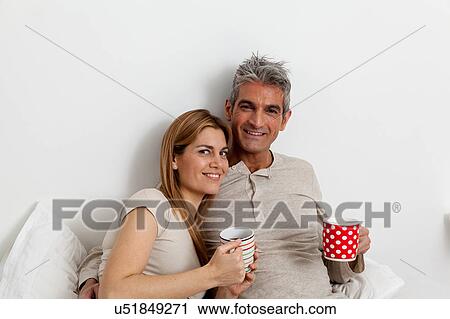 Stock Image - Happy couple drinking tea in the bed. Fotosearch