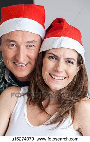 Happy couple in christmas hats View Large Photo Image Stock Photo - Happy couple in christmas hats. Fotosearch