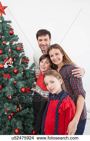 Picture - Happy family beside the christmas tree. Fotosearch
