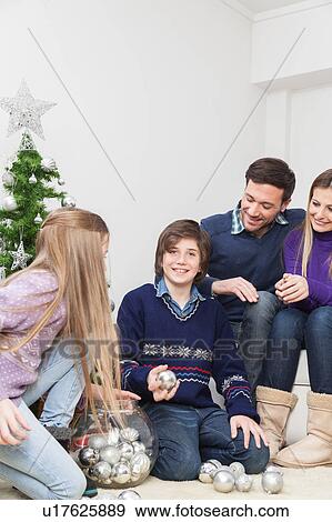 Happy family preparing the christmas tree View Large Photo Image Stock Photo - Happy family preparing the christmas tree. Fotosearch