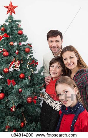 Happy family smiling beside the christmas tree View Large Photo Image Stock Image - Happy family smiling beside the christmas tree. Fotosearch