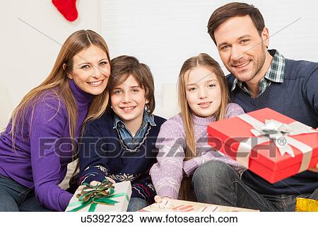 Stock Image - Happy family smiling giving present. Fotosearch