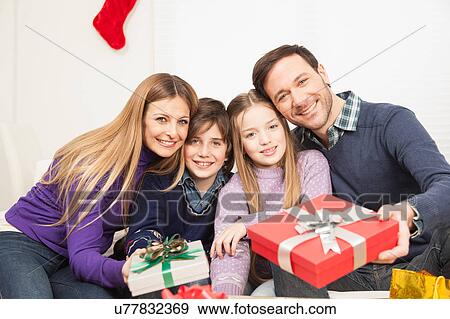 Stock Photo - Happy family smiling giving present. Fotosearch
