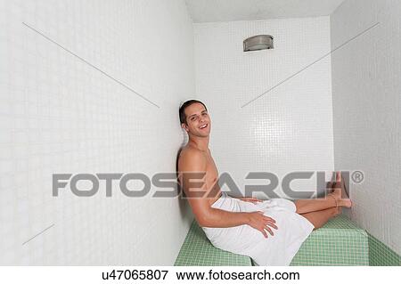 Stock Photo - Happy guy laid inside the sauna. Fotosearch