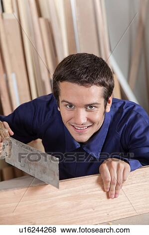 Happy guy using a saw View Large Photo Image Stock Photo - Happy guy using a saw. Fotosearch