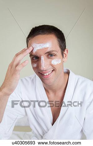 Stock Image - Happy guy with face cream. Fotosearch