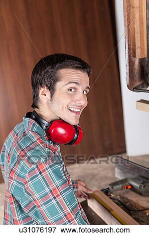 Stock Photo - Happy guy working with wood. Fotosearch