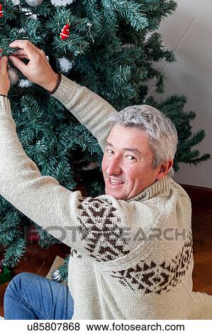 Happy man decorating the christmas tree View Large Photo Image Stock Photo - Happy man decorating the christmas tree. Fotosearch