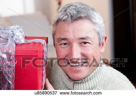 Stock Photo - Happy man holding a gift. Fotosearch