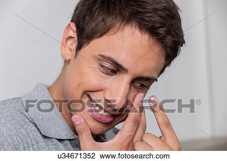Stock Image - Happy man putting the contact lenses. Fotosearch