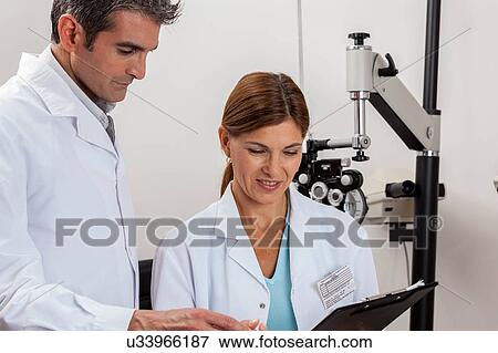 Stock Photo - happy ophthalmologists looking at chart. Fotosearch