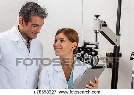 Stock Photo - Happy ophthalmologists looking at tablet. Fotosearch
