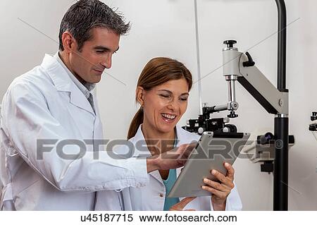Happy ophthalmologists looking at tablet View Large Photo Image Stock Photography - Happy ophthalmologists looking at tablet. Fotosearch
