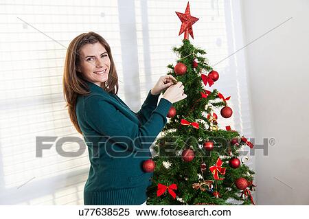 Happy woman decorating christmas tree View Large Photo Image Stock Photography - Happy woman decorating christmas tree. Fotosearch
