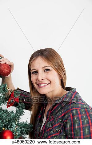 Stock Image - Happy woman holding a ball of the christmas tree. Fotosearch
