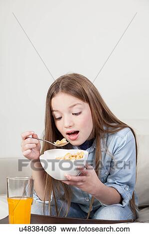 Stock Photo - Little girl eating cereal in the breakfast. Fotosearch