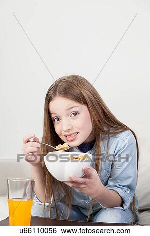 Stock Photograph - Little girl eating cereal in the breakfast. Fotosearch