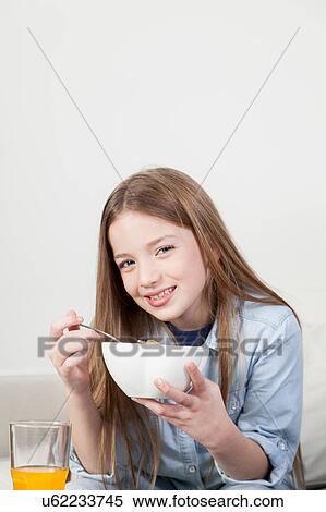 Stock Photography - Little girl eating cereal in the breakfast. Fotosearch