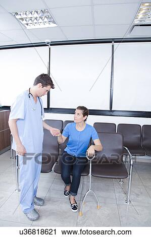 Stock Image - Male nurse helping a woman. Fotosearch